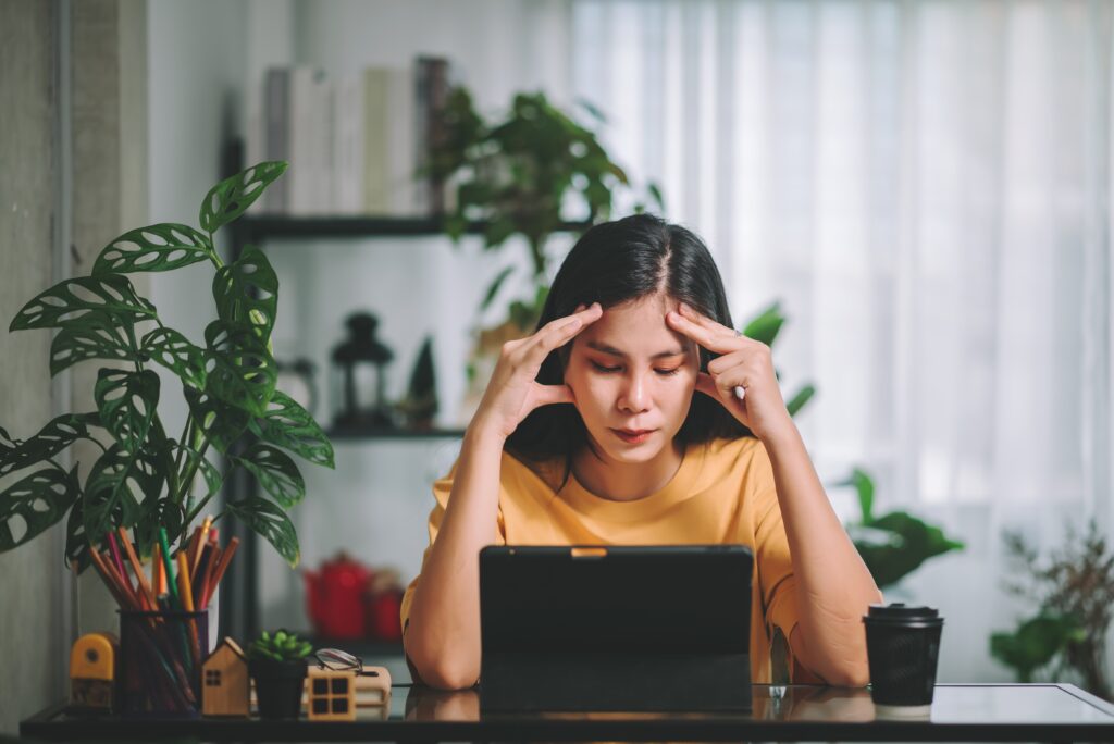 Asian woman in front of laptop feeling stressed